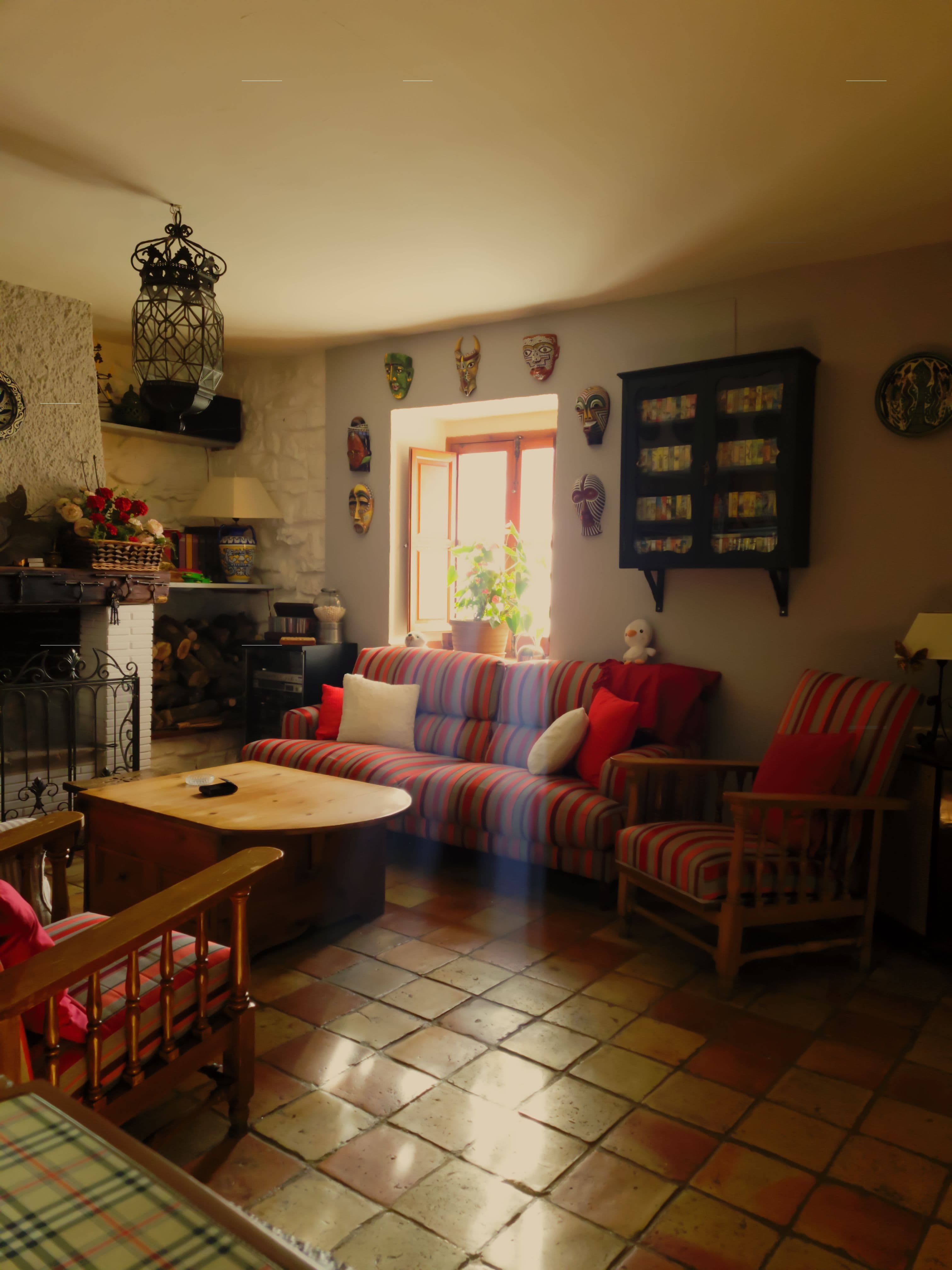 Salón con chimenea de piedra, suelo de barro cocido y mobiliario de madera